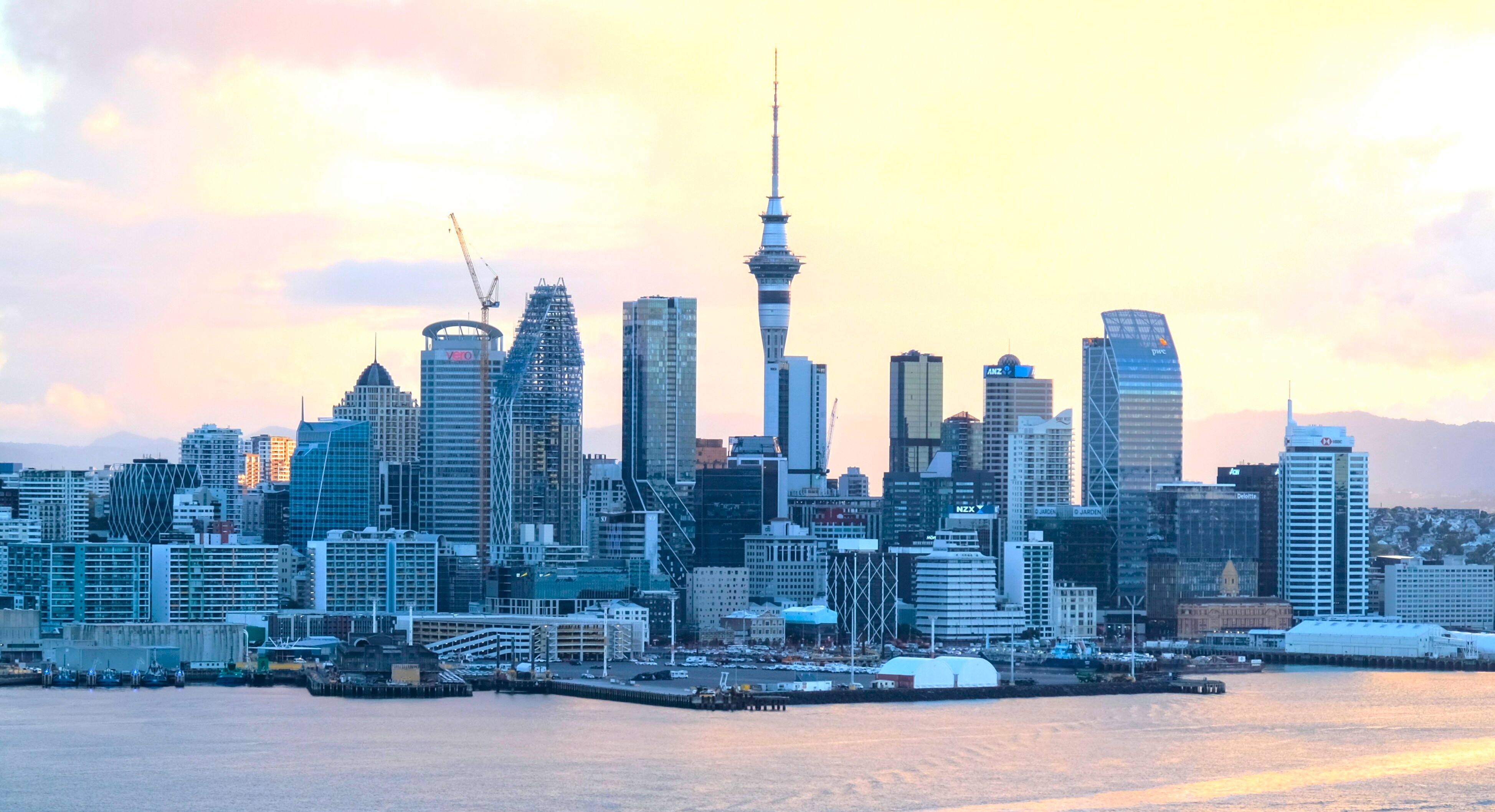 Auckland skyline at sunset, rendered in the site's ink-and-paper duotone style