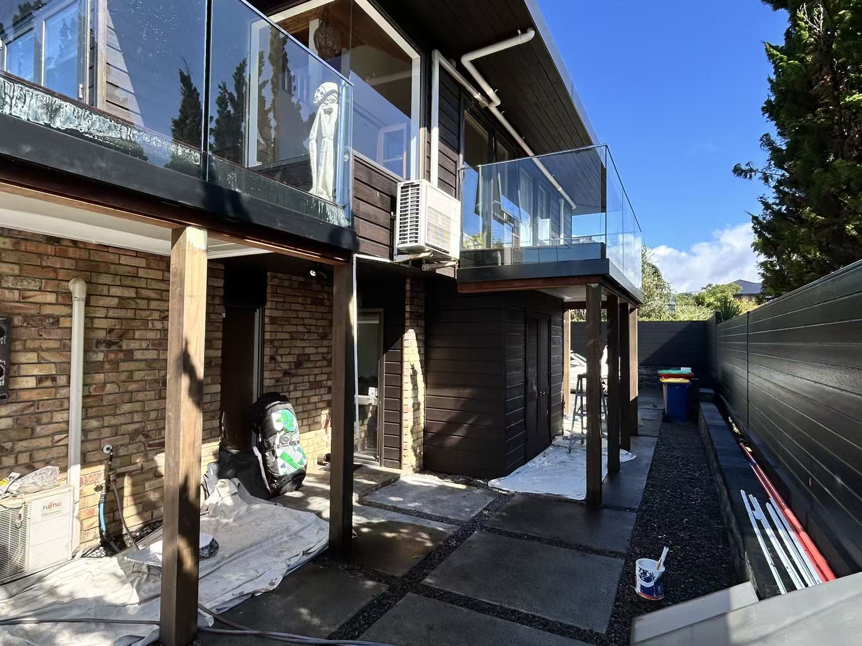 Second-storey addition in progress, rear elevation, showing new upper level with glass balustrade balcony over existing brick ground floor