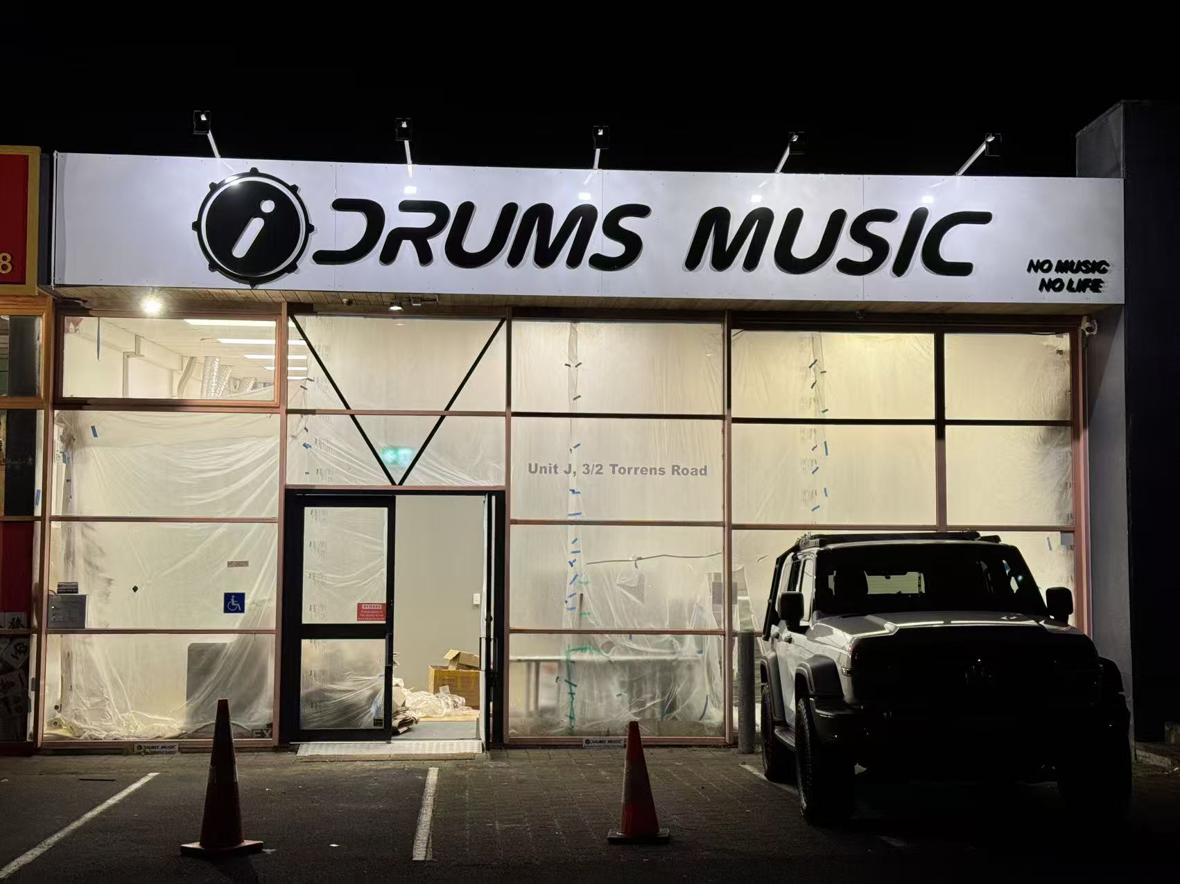 Commercial renovation at night, iDrums Music store front with new glazing and signage